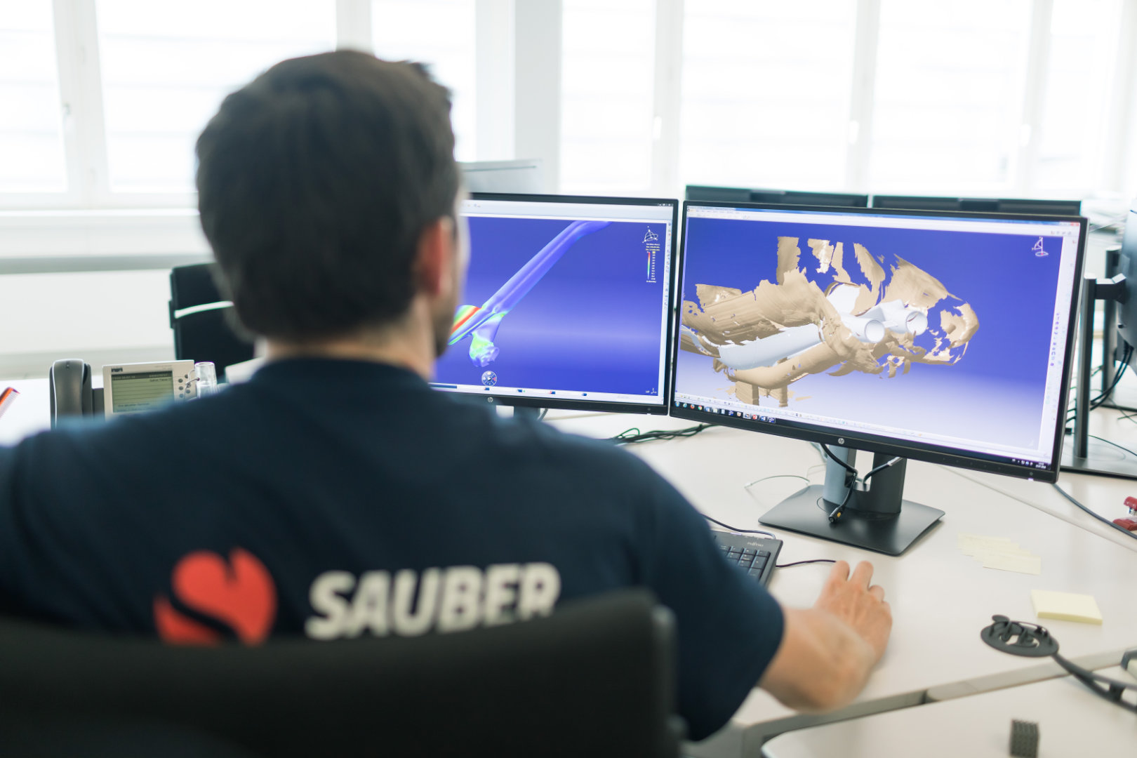 Sauber engineer sits in front of 2 screens